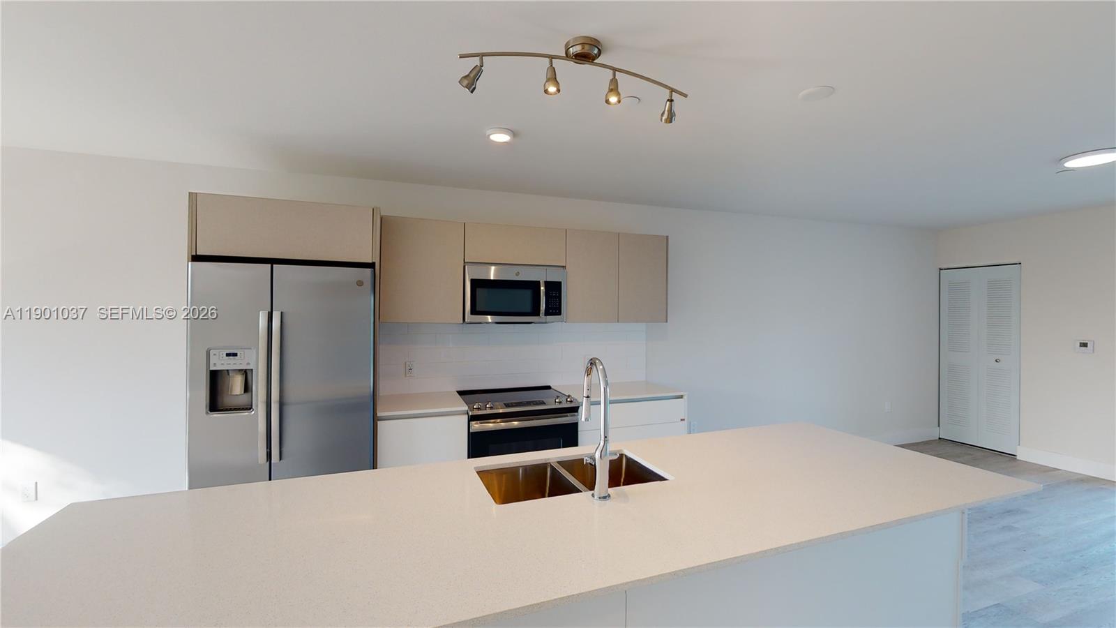A modern kitchen features a large island with a sink, stainless steel appliances, and cabinetry — 2555 NE 193rd St # 2224, Miami FL 33180, MIAMI, FL