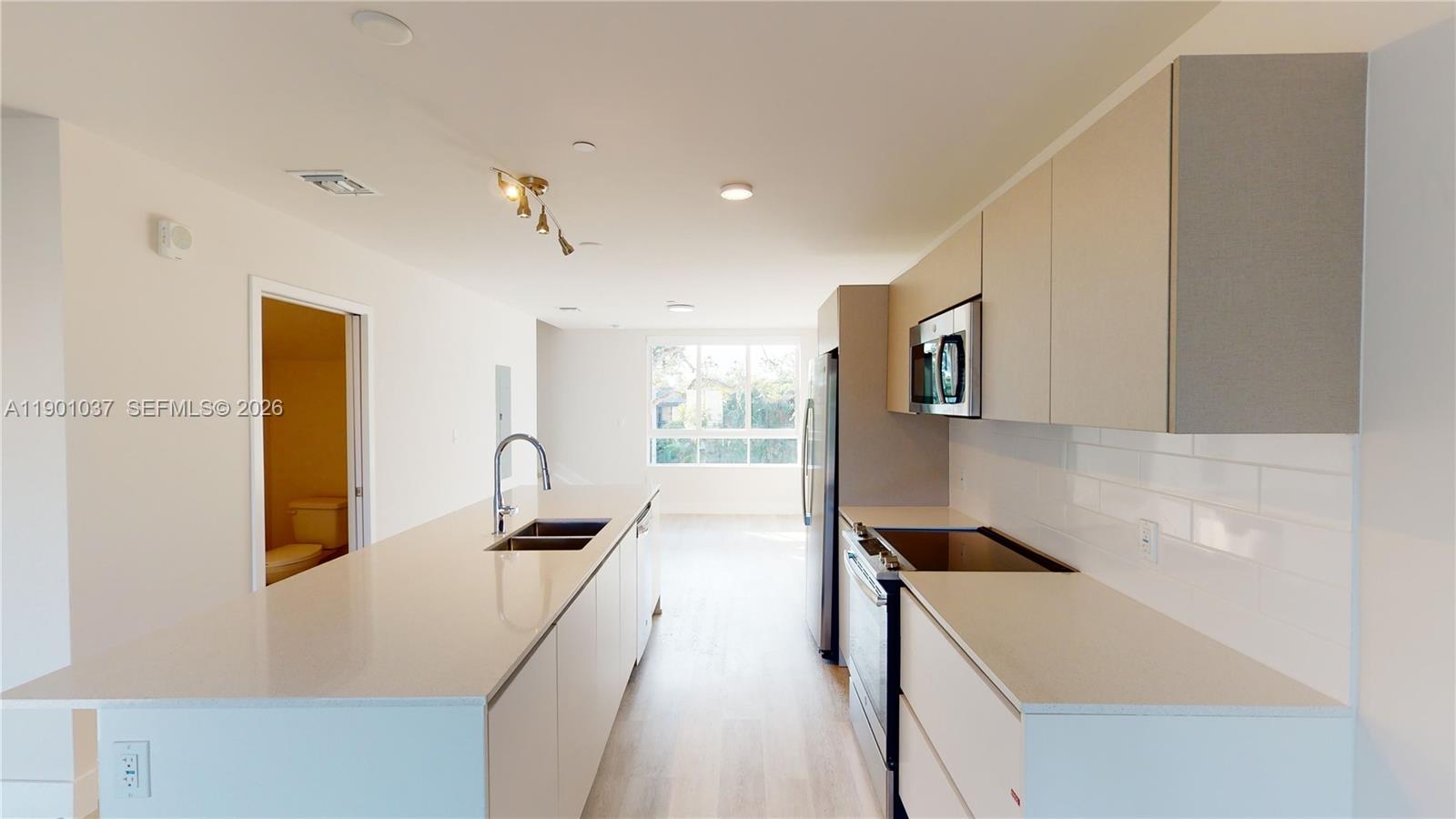 A modern kitchen features a long island, light-colored cabinetry, and stainless steel appliances — 2555 NE 193rd St # 2224, Miami FL 33180, MIAMI, FL