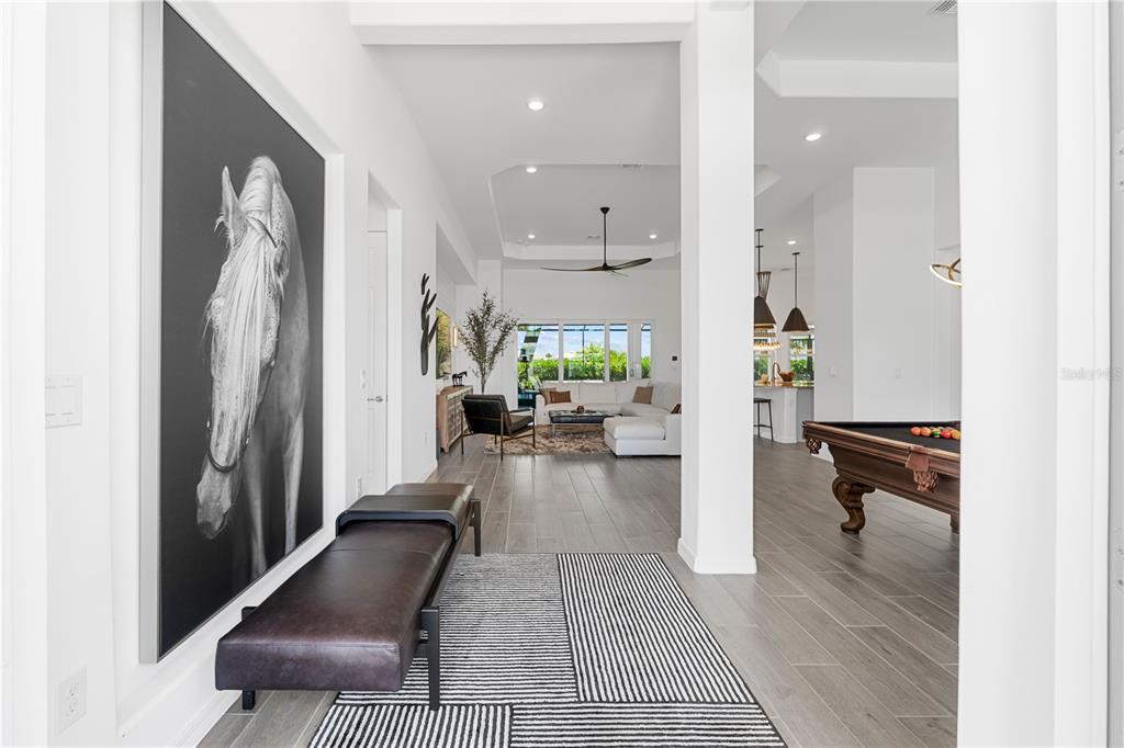 A modern entryway features a large horse portrait, a leather bench, and a striped rug — 15860 CRANES MARSH COURT, PUNTA GORDA, FL