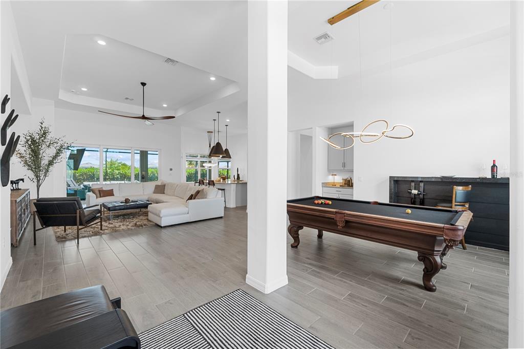 An open-concept living area features a pool table, a white sectional sofa, and tile flooring — 15860 CRANES MARSH COURT, PUNTA GORDA, FL