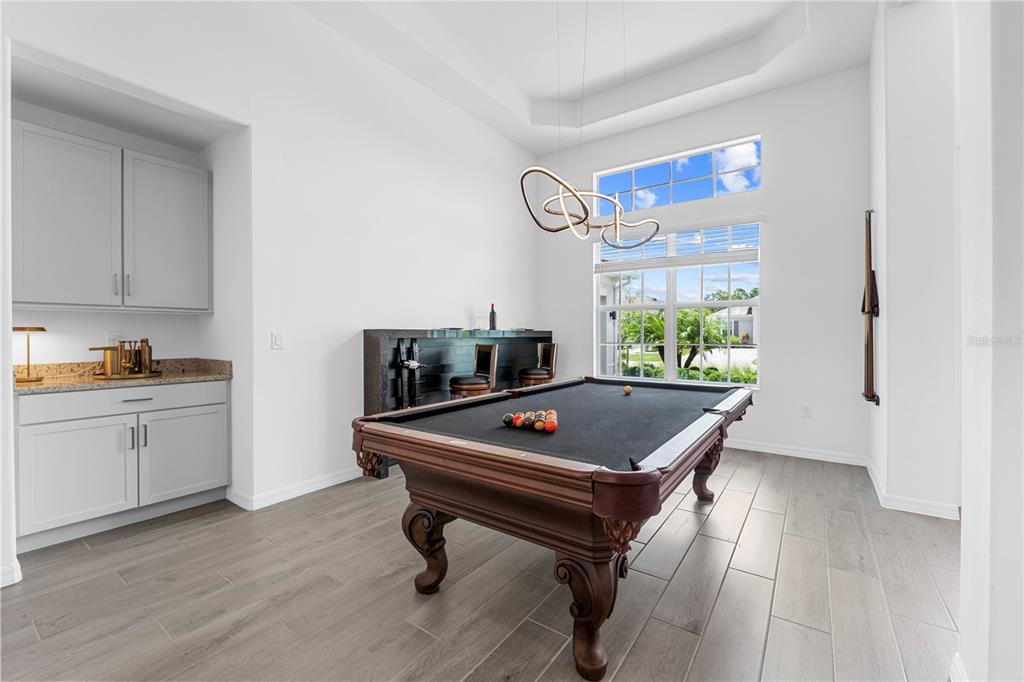 A game room features a pool table, a wet bar, and large windows with natural light — 15860 CRANES MARSH COURT, PUNTA GORDA, FL