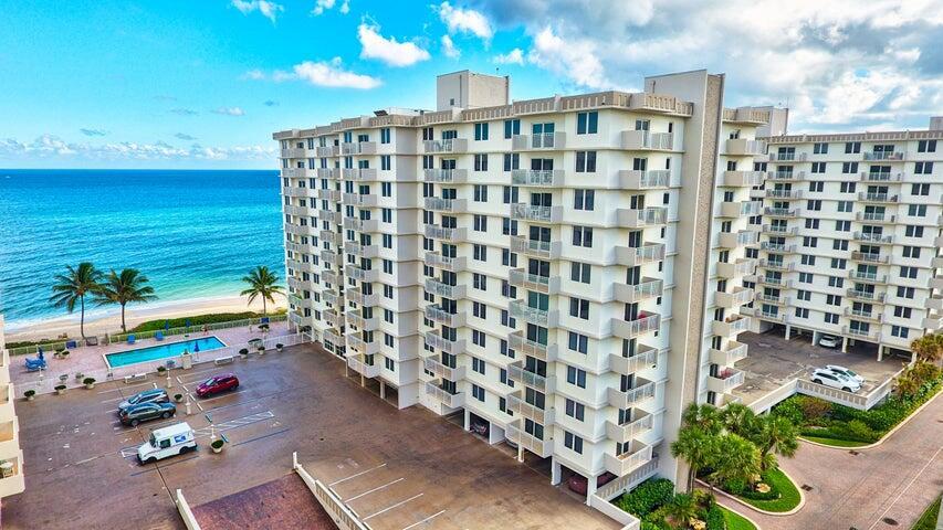 An aerial view of a multi-story beachfront apartment building with a pool and parking lot — 3221 S Ocean Boulevard # 207, Highland Beach FL 33487, HIGHLAND BEACH, FL