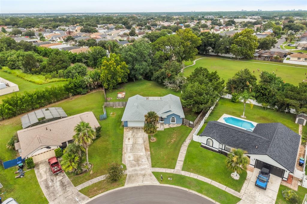An aerial view shows a blue house with a gray roof centered between two neighboring homes — 2556 TANDORI CIRCLE, ORLANDO, FL