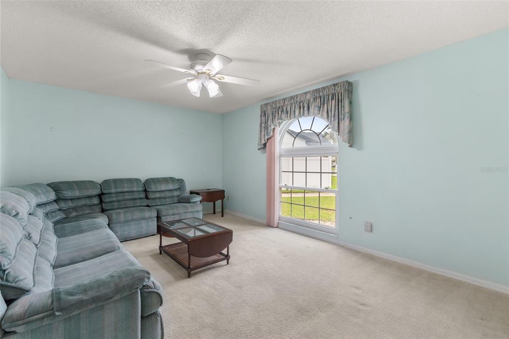 A living room features light blue walls, beige carpeting, a sectional sofa, and an arched window — 2556 TANDORI CIRCLE, ORLANDO, FL