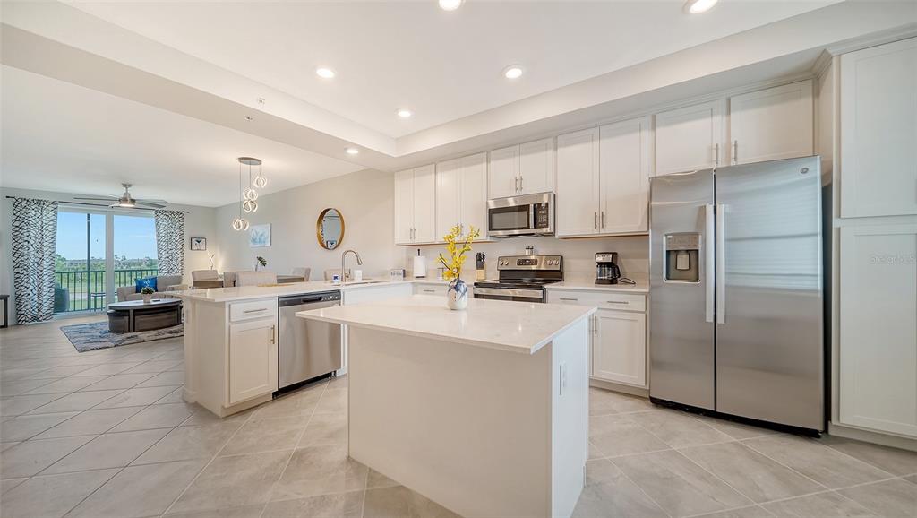 A modern kitchen with white cabinets, stainless steel appliances, and a central island — 12180 WELLEN GOLF STREET UNIT 205, VENICE, FL