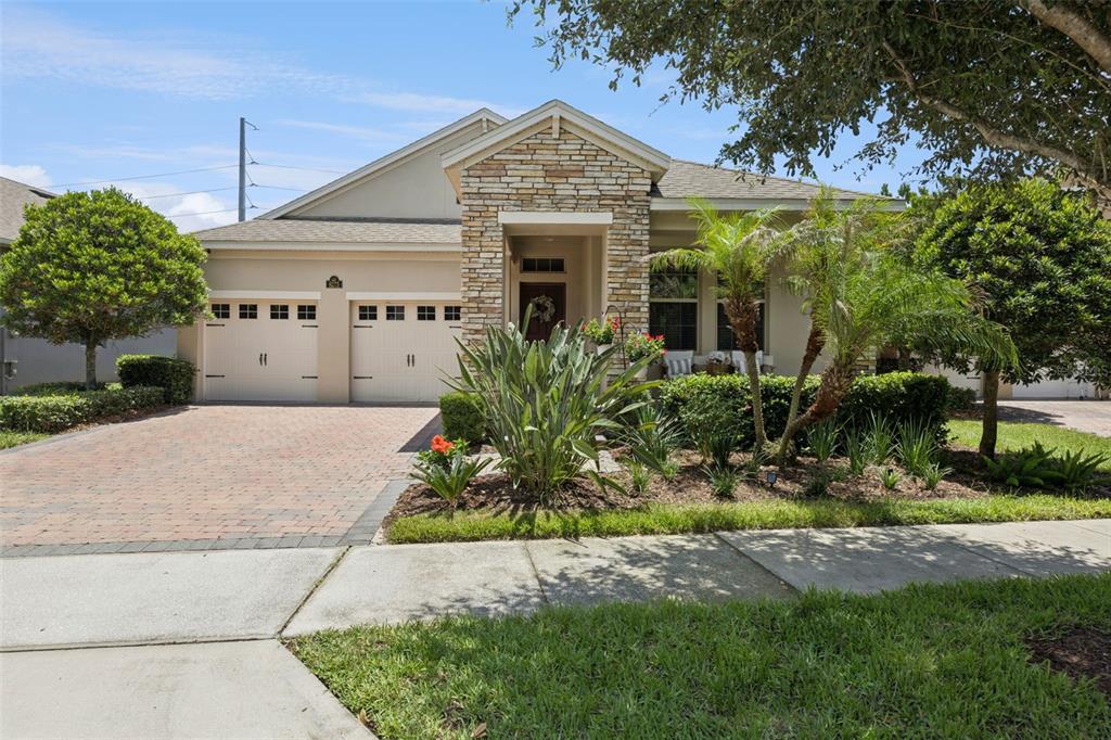 A single-story house with a stone facade, two-car garage, and a paved driveway — 8275 BAYVIEW CROSSING DRIVE, WINTER GARDEN, FL
