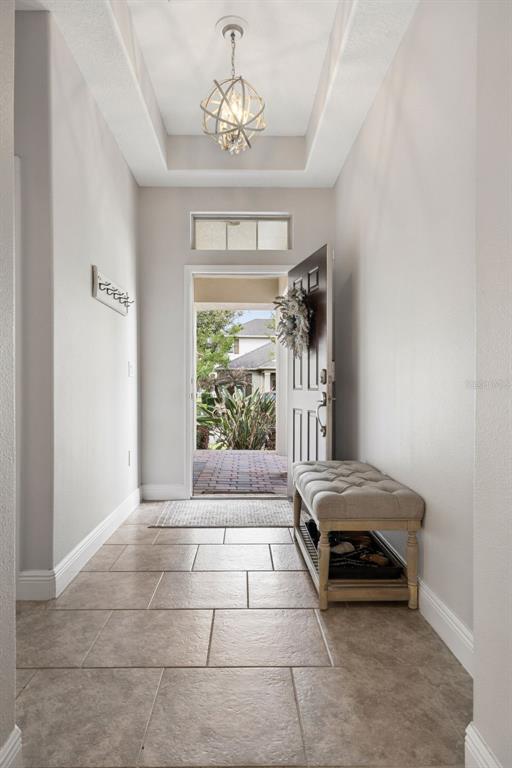 An entryway features tile flooring, a tufted bench, a coat rack, and a pendant light — 8275 BAYVIEW CROSSING DRIVE, WINTER GARDEN, FL