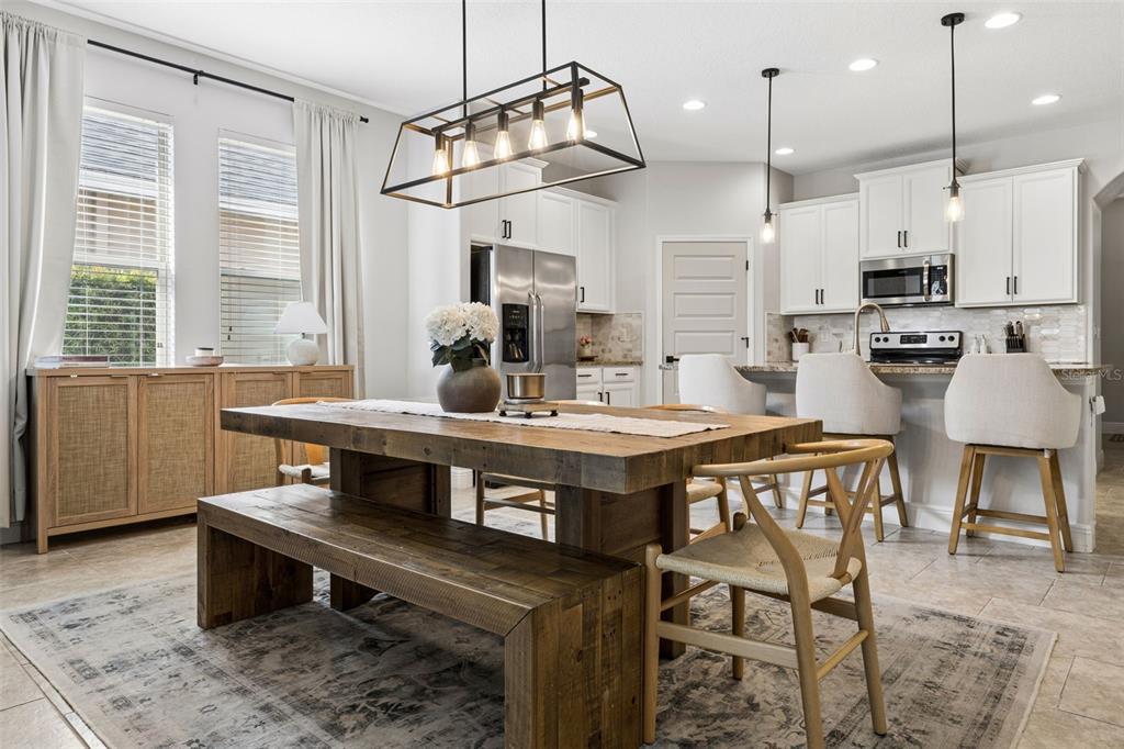 A dining area with a wooden table and bench sits in front of an open kitchen — 8275 BAYVIEW CROSSING DRIVE, WINTER GARDEN, FL