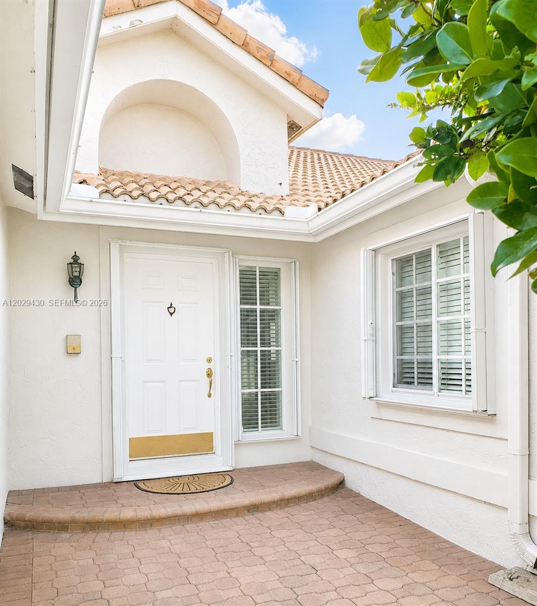 A white front door with a brass kickplate sits on a brick-paved entryway — 569 Spinnaker, Weston FL 33326, WESTON, FL