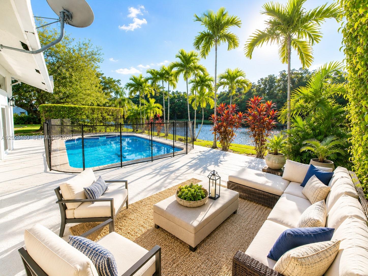 A patio with outdoor furniture and a swimming pool overlooking a lake and palm trees — 569 Spinnaker, Weston FL 33326, WESTON, FL