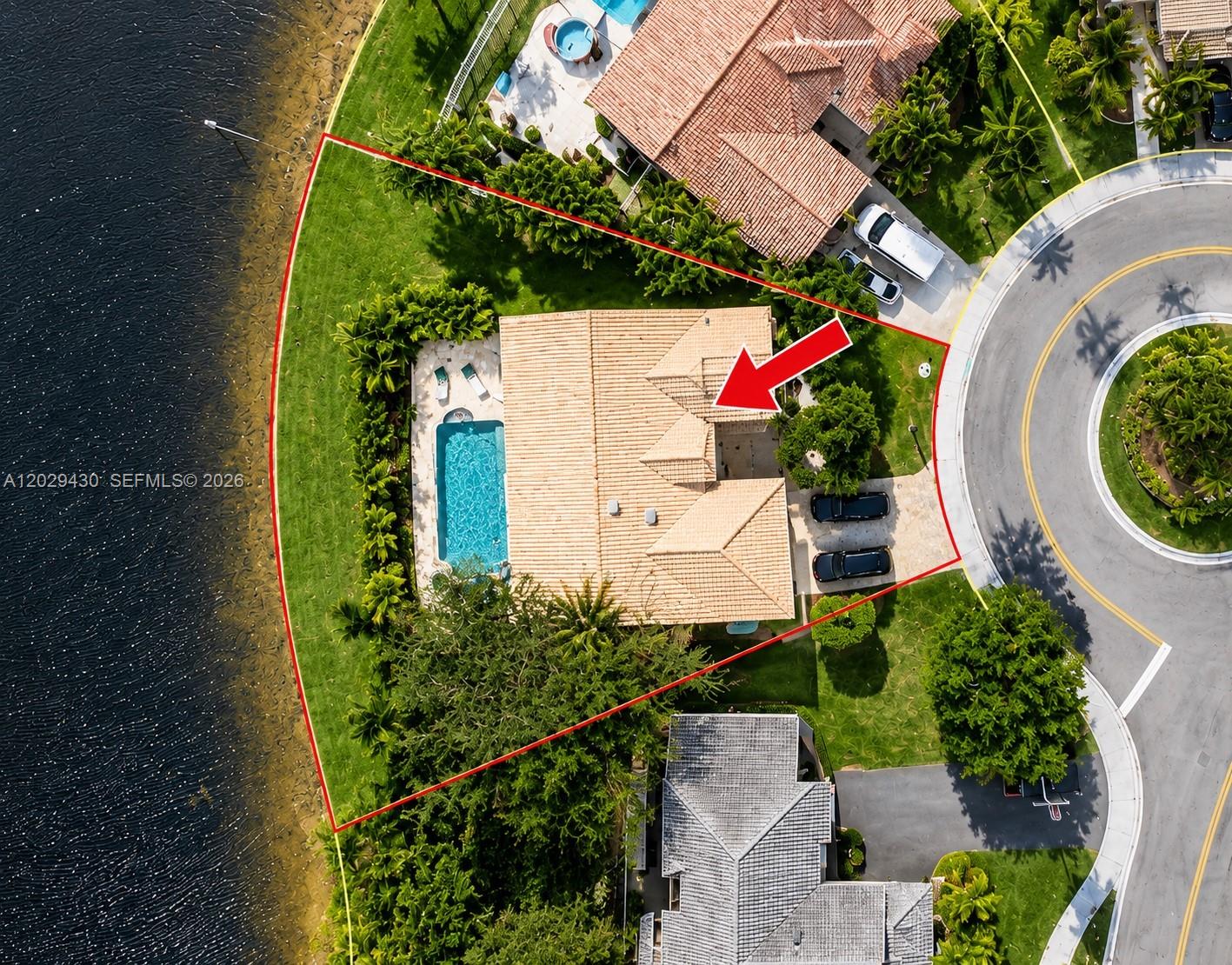 This aerial view shows a house with a pool and driveway on a waterfront lot — 569 Spinnaker, Weston FL 33326, WESTON, FL