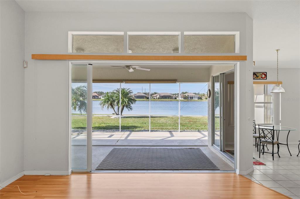 A view from a living room through sliding glass doors to a screened-in patio — 12942 SW KINGSWAY CIRCLE, LAKE SUZY, FL