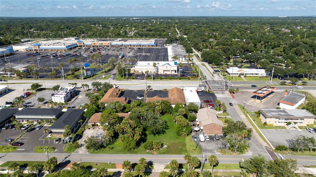 An aerial view shows a commercial area with parking lots, buildings, and surrounding trees — PALMETTO AVENUE, SOUTH DAYTONA, FL