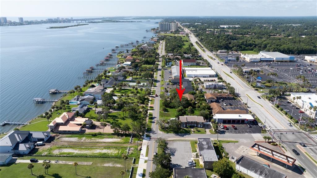 An aerial view shows a residential property surrounded by trees near a coastal waterway — PALMETTO AVENUE, SOUTH DAYTONA, FL