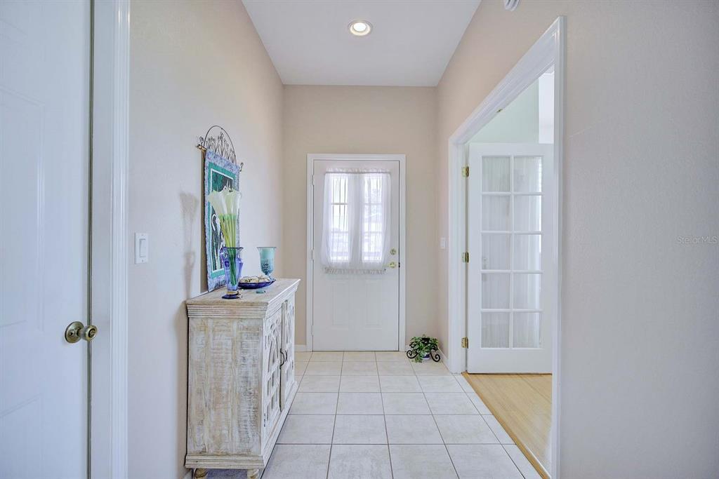 A tiled entryway features a white cabinet, a front door with curtains, and French doors — 2117 VANTAGE TRACE, SEBRING, FL