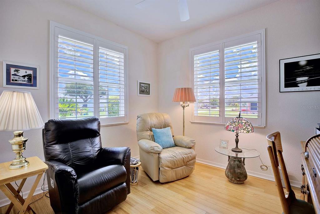 A room with light wood floors, two armchairs, two lamps, and windows with white shutters — 2117 VANTAGE TRACE, SEBRING, FL
