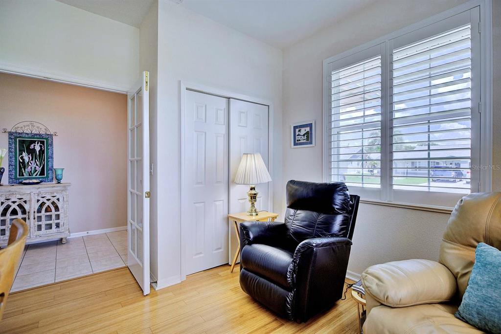 A room with light wood flooring, a black leather recliner, and white plantation shutters — 2117 VANTAGE TRACE, SEBRING, FL