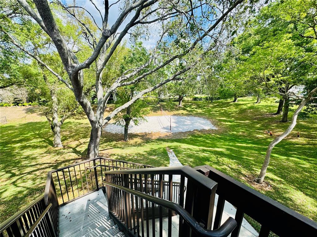A view from a wooden staircase looking down at a grassy yard with a volleyball court — 385 WOODSIDE DRIVE UNIT 201, ALTAMONTE SPRINGS, FL