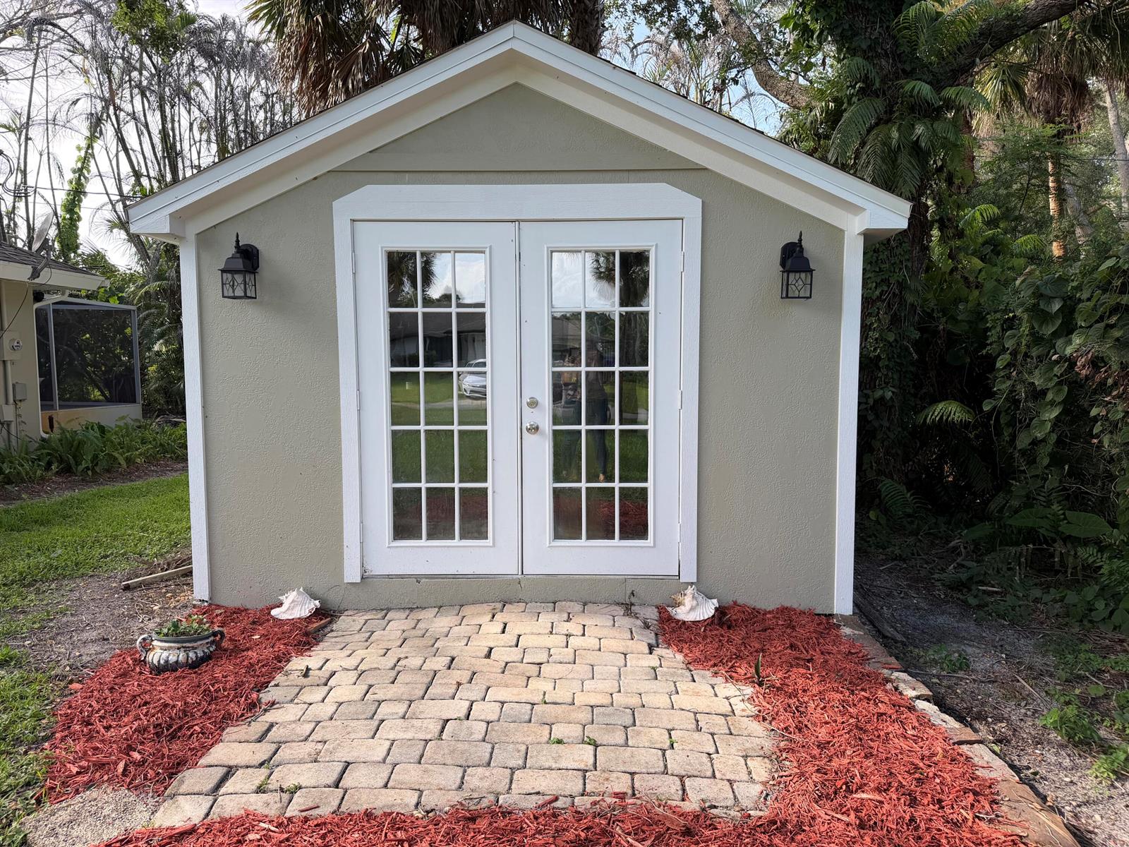 A light green shed with white trim, French doors, and a brick paver walkway — 1290 5th Place, Vero Beach FL 32962, VERO BEACH, FL