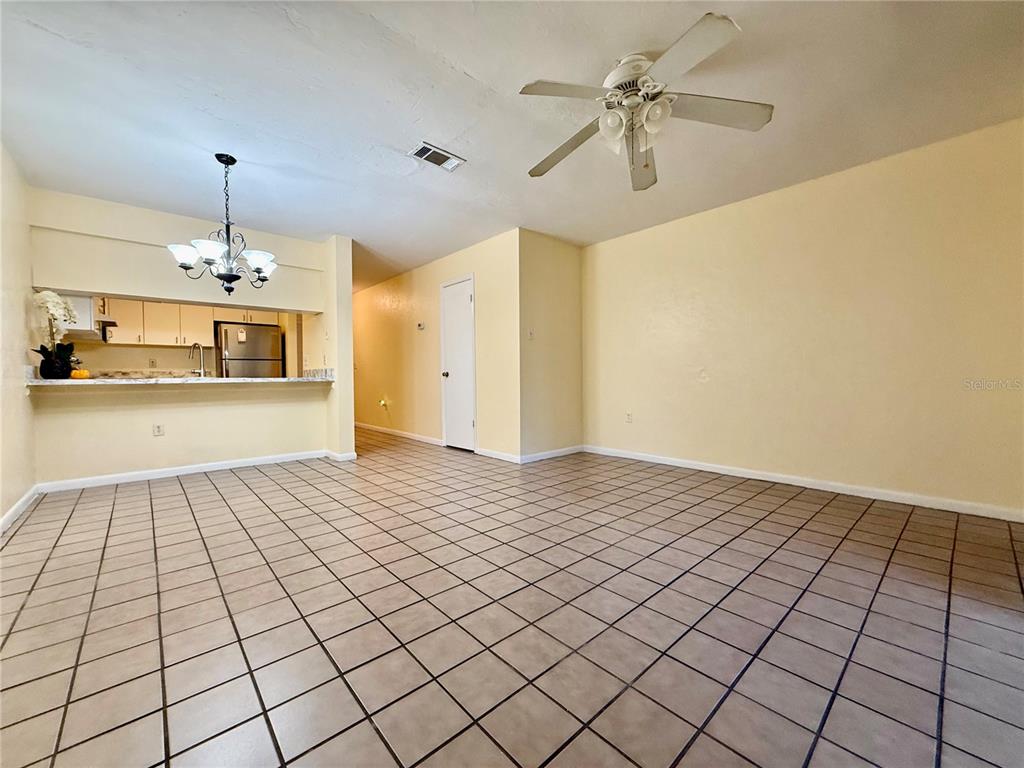 An open-concept living and dining area features light yellow walls and beige tiled flooring — 2735 SW 35TH PLACE UNIT 1604, GAINESVILLE, FL