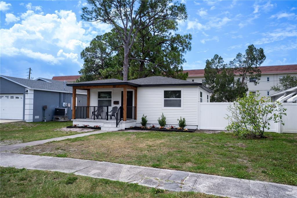 A white single-story house features a front porch with wooden posts and a black railing — 326 41ST AVENUE N, ST PETERSBURG, FL