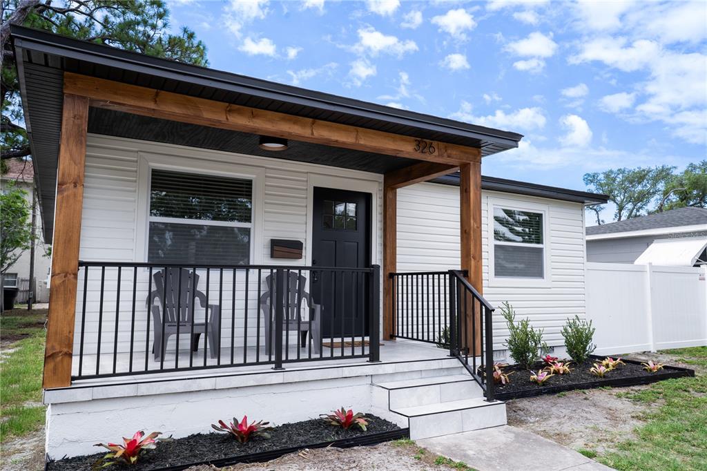 A white house with a covered front porch featuring wood posts and black railings — 326 41ST AVENUE N, ST PETERSBURG, FL