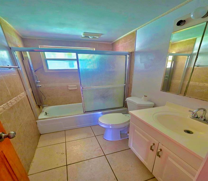 A bathroom features a tiled tub-shower combination, a white vanity, and a toilet — 3806 BADEN DRIVE, HOLIDAY, FL