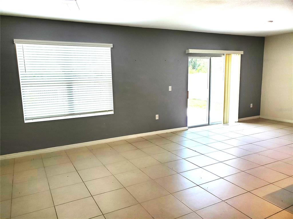 A living room features gray walls, tile flooring, a large window, and a sliding glass door — 32871 BROOKS HAWK LANE, WESLEY CHAPEL, FL