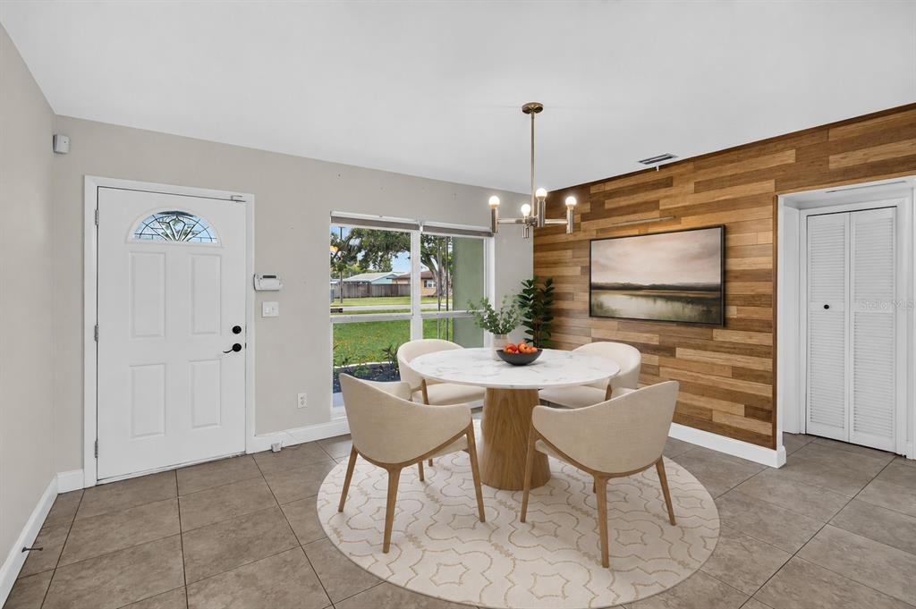 A dining area features a round marble table, four chairs, and a wood-paneled accent wall — 2125 N HERCULES AVENUE, CLEARWATER, FL