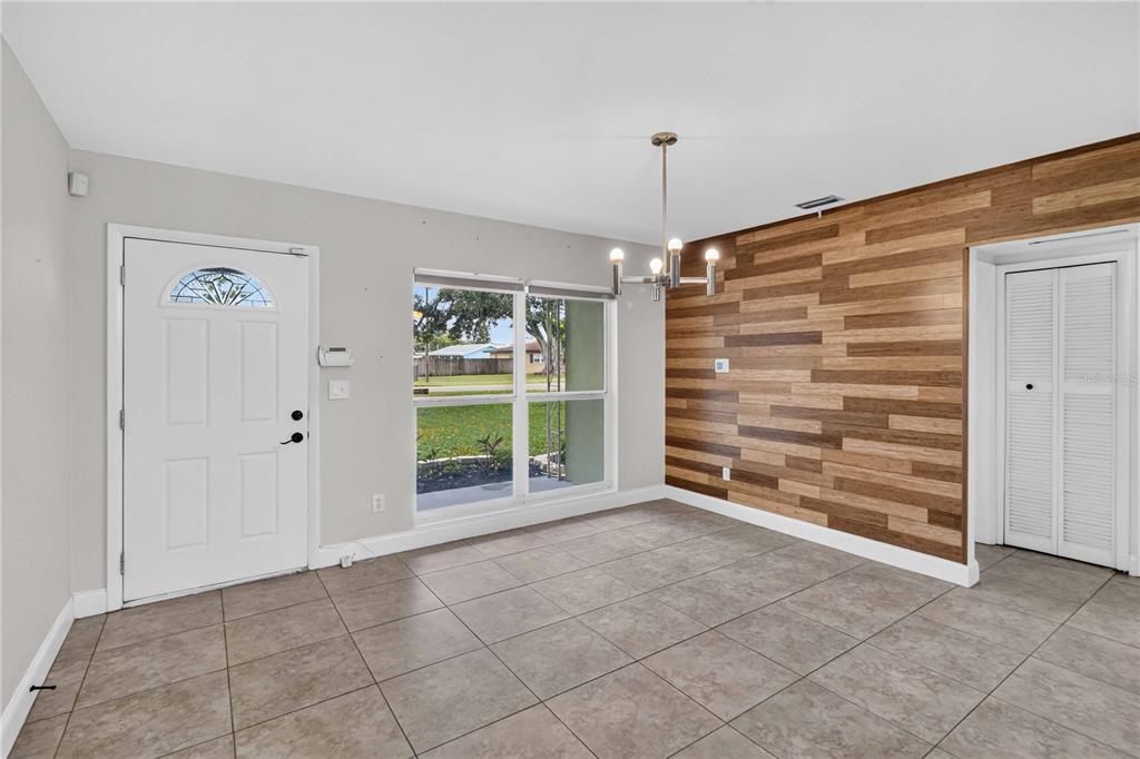 A dining room features tile flooring, a wood-paneled accent wall, and a white front door — 2125 N HERCULES AVENUE, CLEARWATER, FL