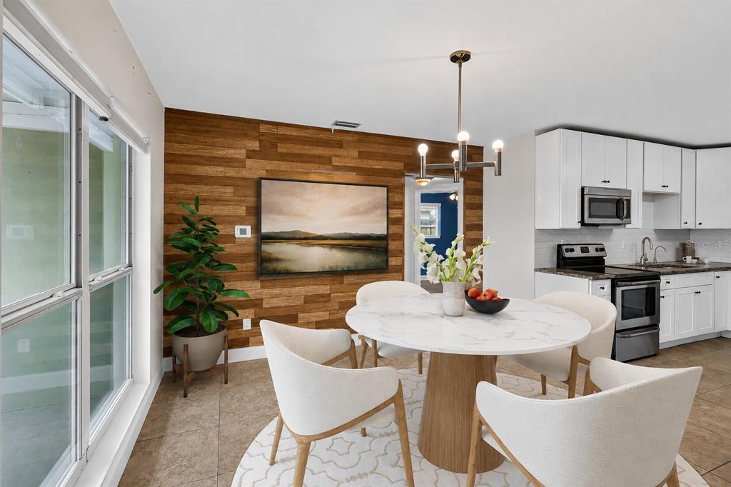 A dining area features a wood-paneled accent wall, a round marble table, and white chairs — 2125 N HERCULES AVENUE, CLEARWATER, FL