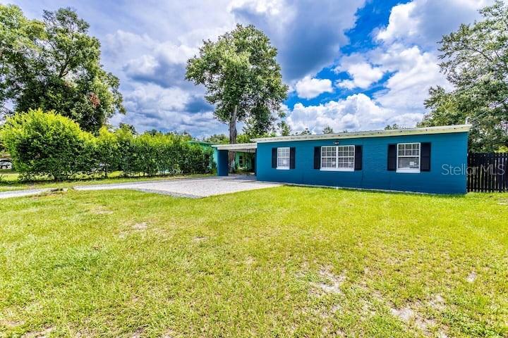 A teal single-story house with black shutters sits on a grassy lot under a cloudy sky — 511 SAN JUAN BOULEVARD, ORLANDO, FL
