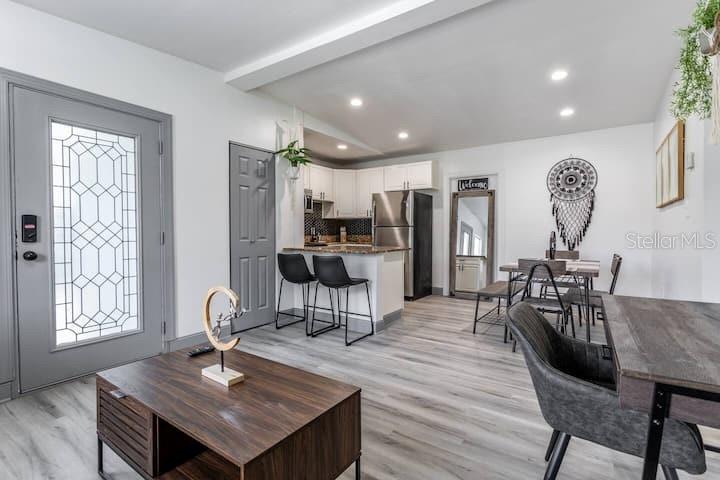 An open-concept living and dining area features light wood-look flooring, white cabinetry, and gray doors — 511 SAN JUAN BOULEVARD, ORLANDO, FL