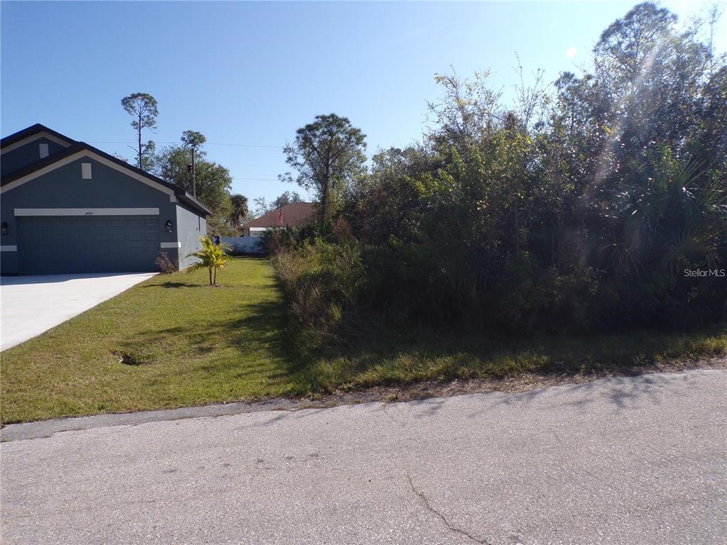 A paved street borders a grassy residential lot next to a house with a garage — 3490 DUNKIRK STREET, PUNTA GORDA, FL