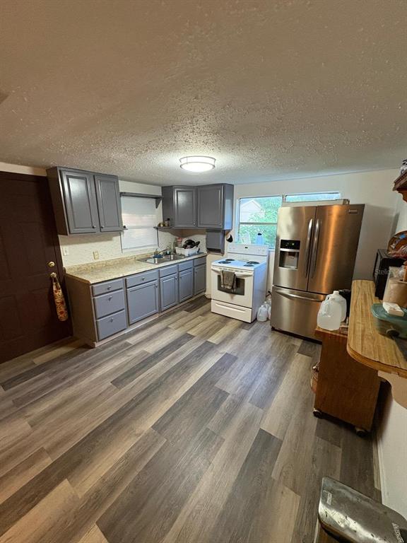 A kitchen features gray cabinets, stainless steel appliances, and wood-look flooring — 18112 ALT STREET, SPRING HILL, FL