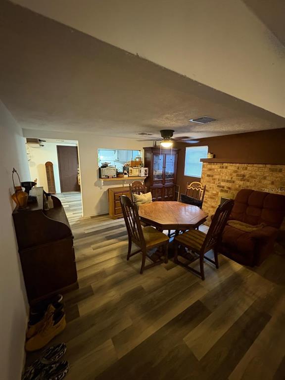 A dining area features a wooden table, chairs, and a brick fireplace on wood-look flooring — 18112 ALT STREET, SPRING HILL, FL
