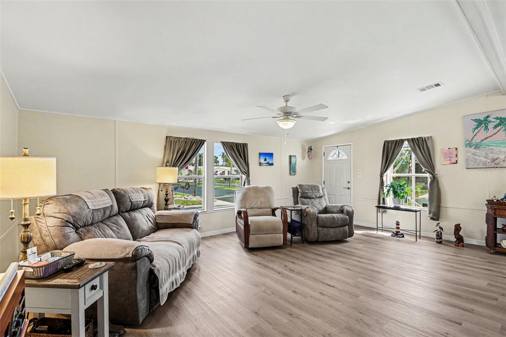A living room features light wood-look flooring, a ceiling fan, and a gray sofa — 1000 KINGS HIGHWAY UNIT 366, PUNTA GORDA, FL