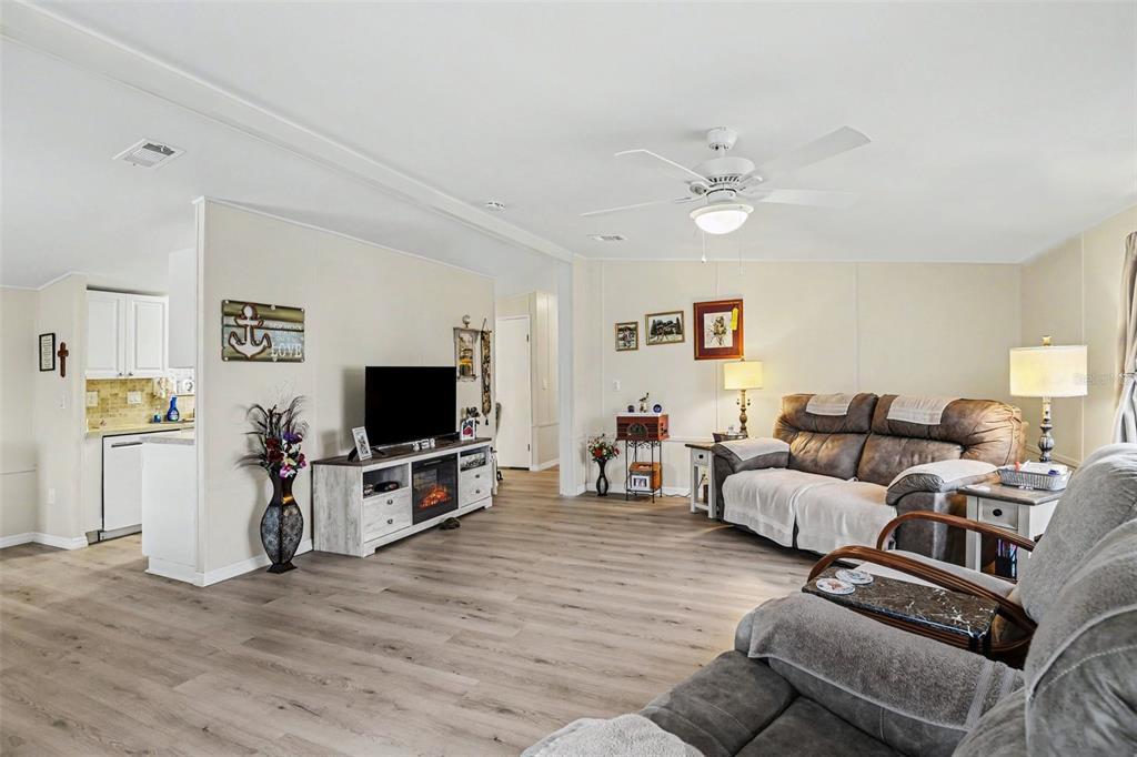 A living room with wood-look flooring, a fireplace console, and a brown reclining sofa — 1000 KINGS HIGHWAY UNIT 366, PUNTA GORDA, FL