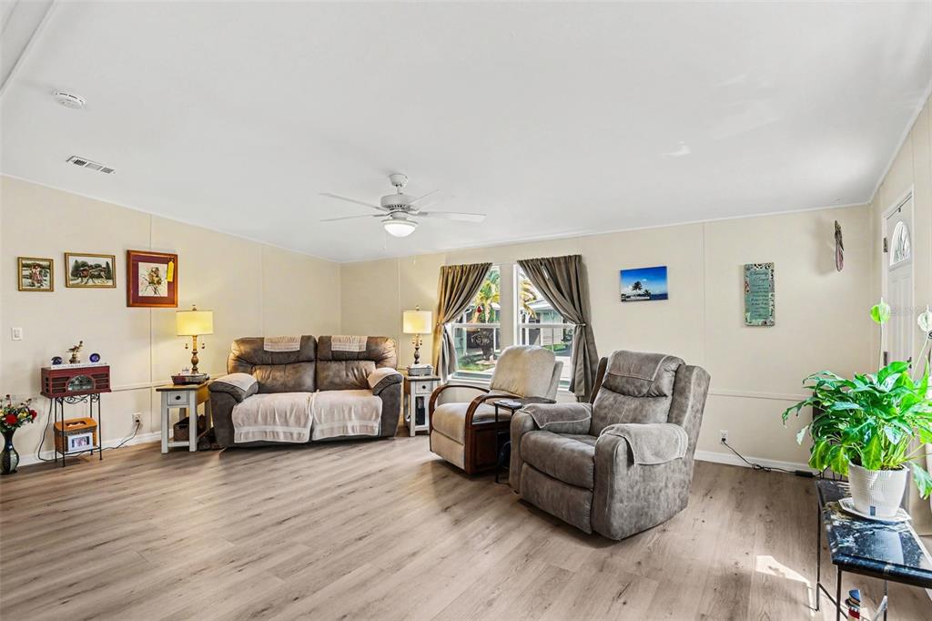 A living room features light wood-look flooring, a ceiling fan, and neutral-colored walls — 1000 KINGS HIGHWAY UNIT 366, PUNTA GORDA, FL