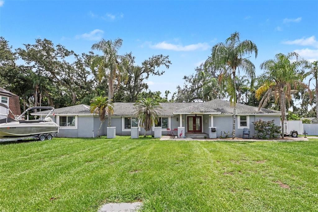 A single-story gray house with a boat parked on the lawn and palm trees — 1307 BRANTWOOD DRIVE, VALRICO, FL