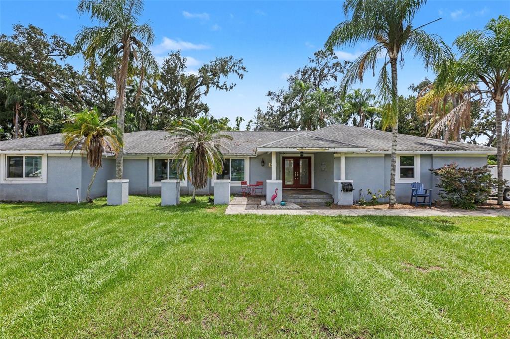 A single-story gray house with a lawn, palm trees, and a front entryway — 1307 BRANTWOOD DRIVE, VALRICO, FL