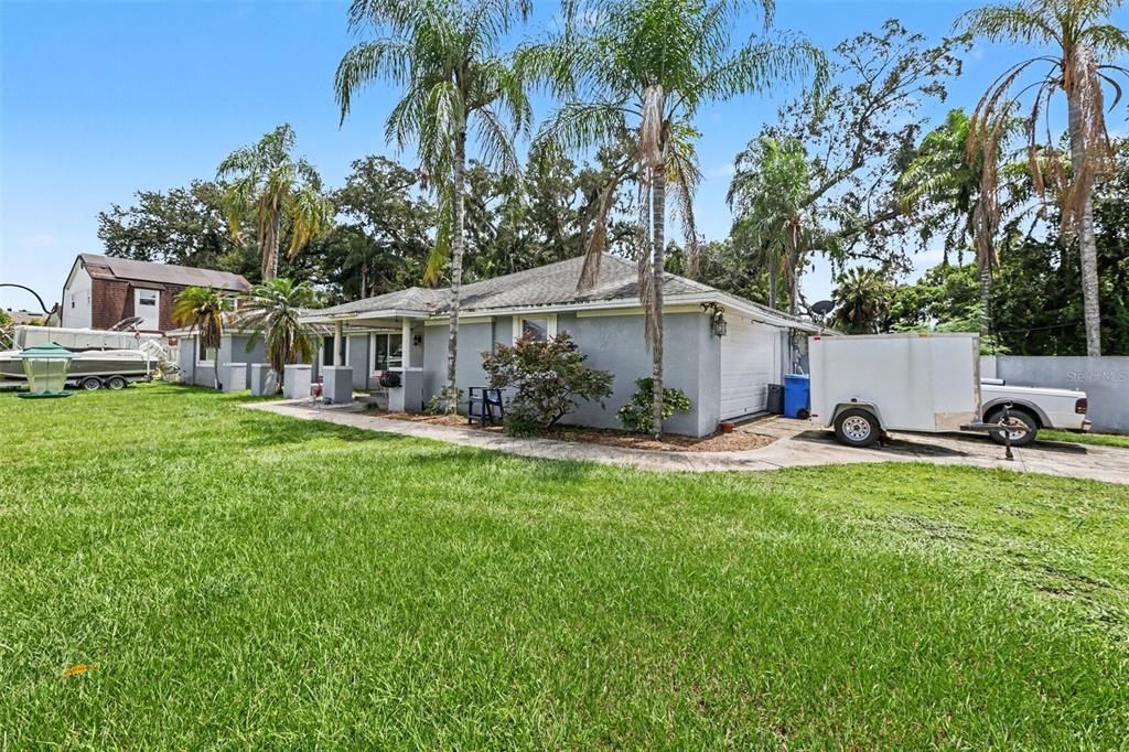 A single-story house with a gray exterior, a white garage door, and a large grassy yard — 1307 BRANTWOOD DRIVE, VALRICO, FL