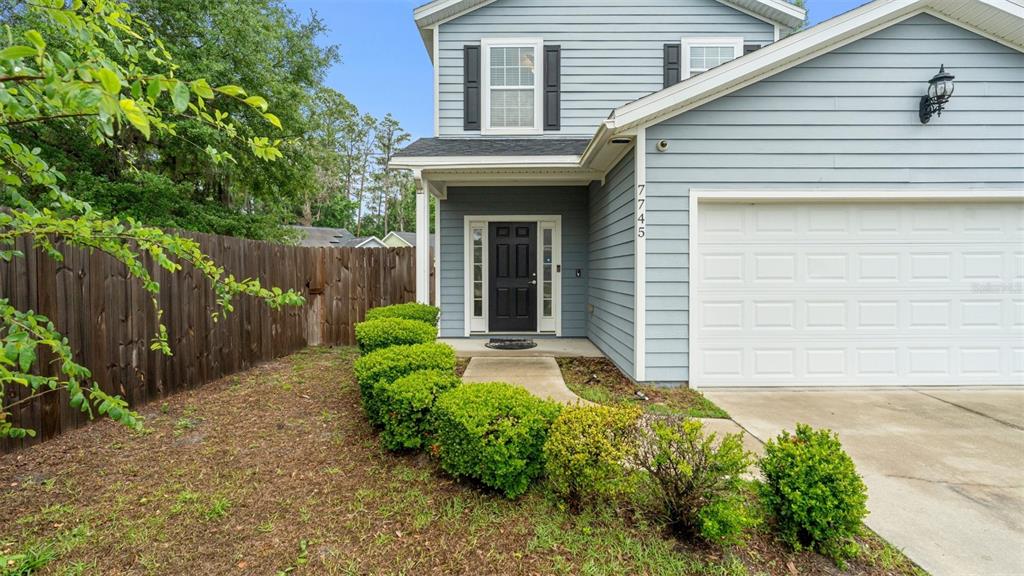 A two-story house with blue siding, a black front door, and a white garage door — 7745 NW 20TH WAY, GAINESVILLE, FL