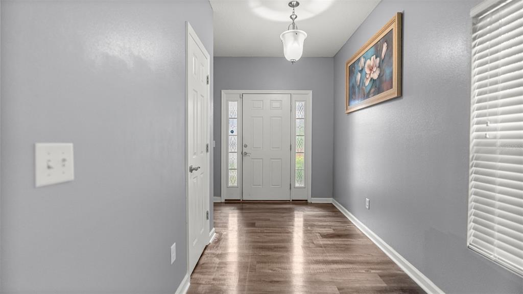 An entryway with gray walls, wood-look flooring, a white front door, and a hanging light fixture — 7745 NW 20TH WAY, GAINESVILLE, FL