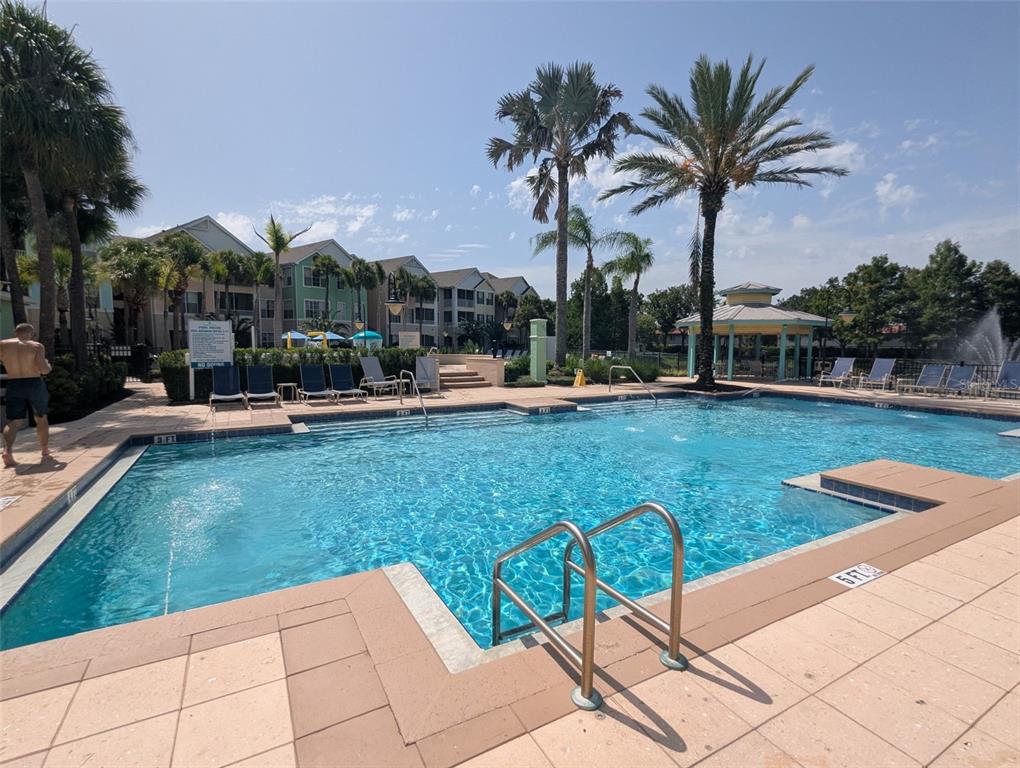 A swimming pool with a fountain and lounge chairs sits in front of apartment buildings — 3003 LIMBO LANE UNIT 203, KISSIMMEE, FL