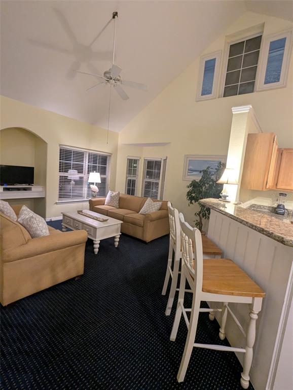 A living room with a vaulted ceiling, tan sofa, and a kitchen bar with stools — 3003 LIMBO LANE UNIT 203, KISSIMMEE, FL