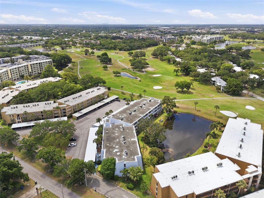 An aerial view shows several multi-story apartment buildings surrounding a pond and a golf course — 225 COUNTRY CLUB DRIVE UNIT C332, LARGO, FL