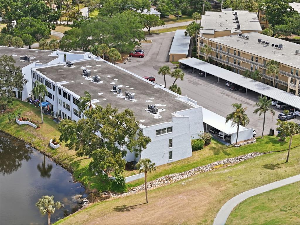 An aerial view shows two multi-story apartment buildings with parking carports and a small pond — 225 COUNTRY CLUB DRIVE UNIT C332, LARGO, FL