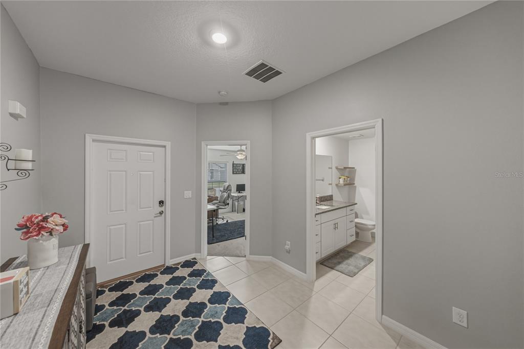 An entryway with tile flooring, a white front door, and doorways leading to other rooms — 2922 FLYING BLACKBIRD ROAD, BARTOW, FL