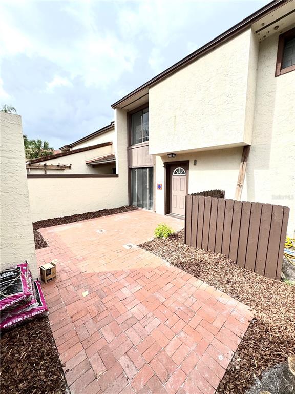 A brick patio leads to the front entrance of a two-story townhouse with stucco siding — 4229 S LAKE ORLANDO PARKWAY UNIT 133, ORLANDO, FL